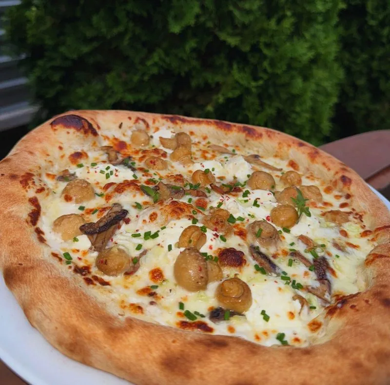 Pizza albă cu ciuperci, cu marginea pufoasă și rumenită pe vatră