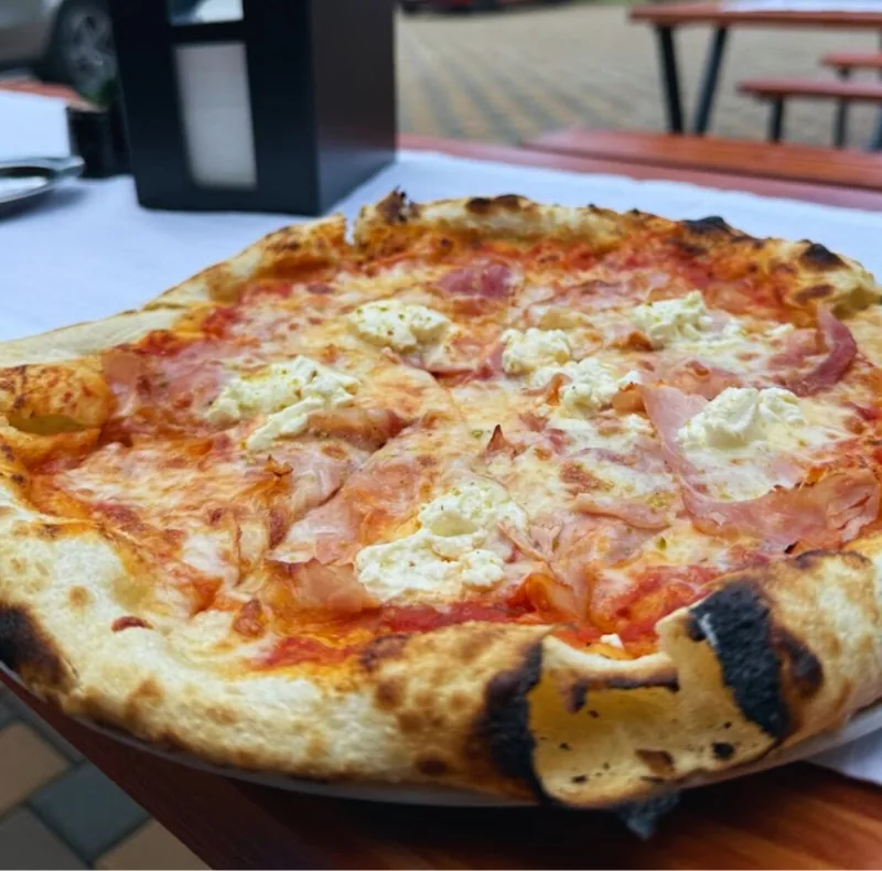 Pizza cu prosciutto cotto și cremă de brânză, servită pe terasă
